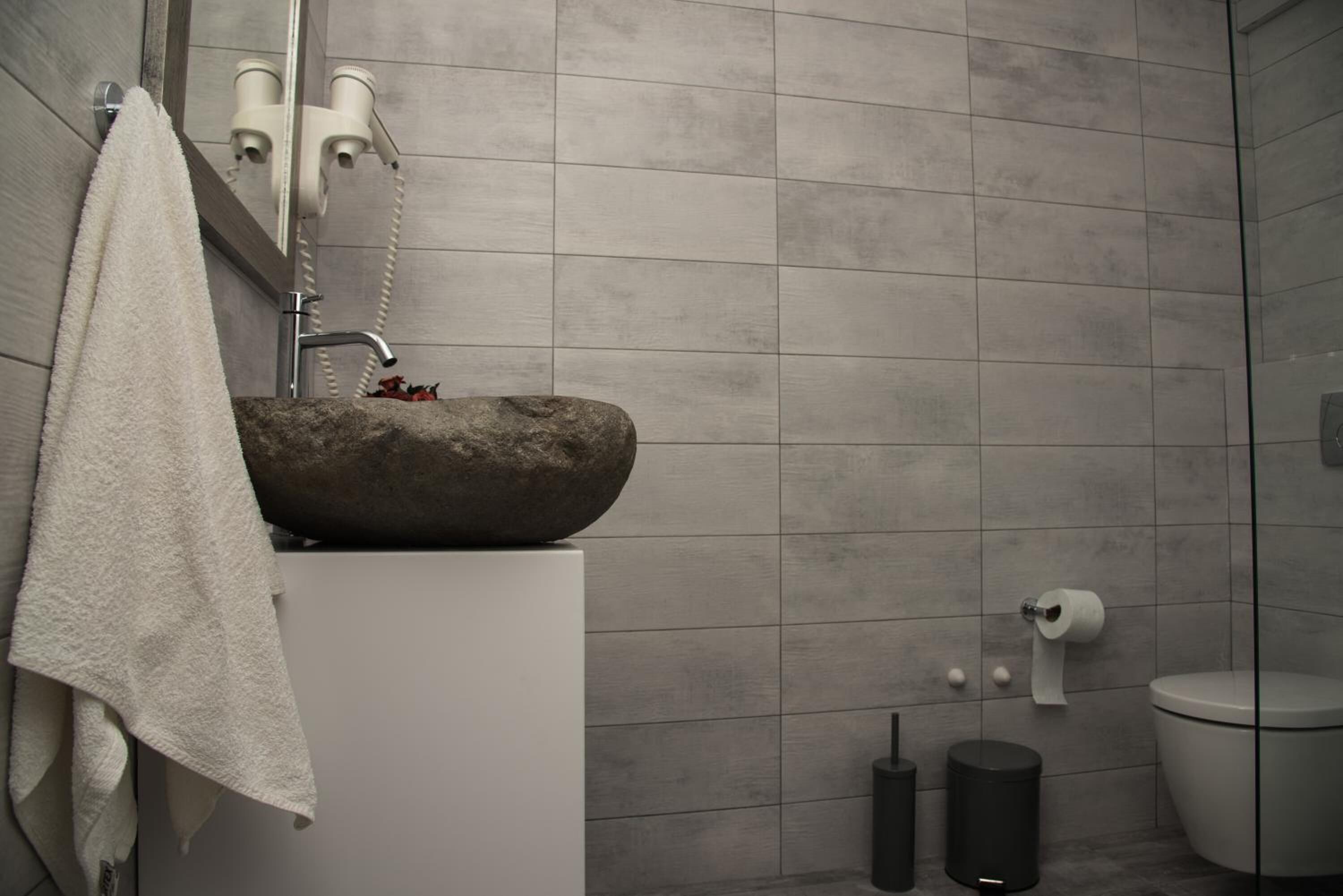 A bathroom with a stone sink, a towel hanging on the wall, and a toilet.