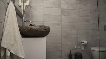 A bathroom with a stone sink, a towel hanging on the wall, and a toilet.