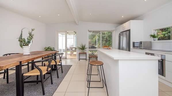 Una cocina moderna con una mesa de comedor de madera, taburetes de bar y una encimera blanca.