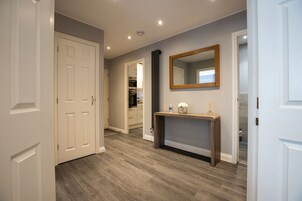A hallway with a wooden console table, a mirror, and a door leading to a closet.