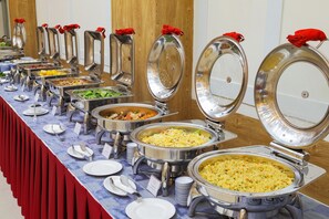 A buffet with multiple food stations, each with a metal serving tray and a red cloth on top. - T78 Hotel Managed By Nha Khach T78 (Ho Chi Minh City)