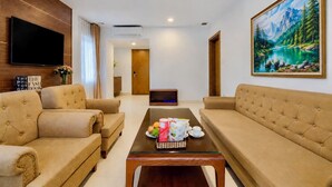A living room with two sofas, a coffee table with snacks, a TV, and a painting of a mountain landscape.