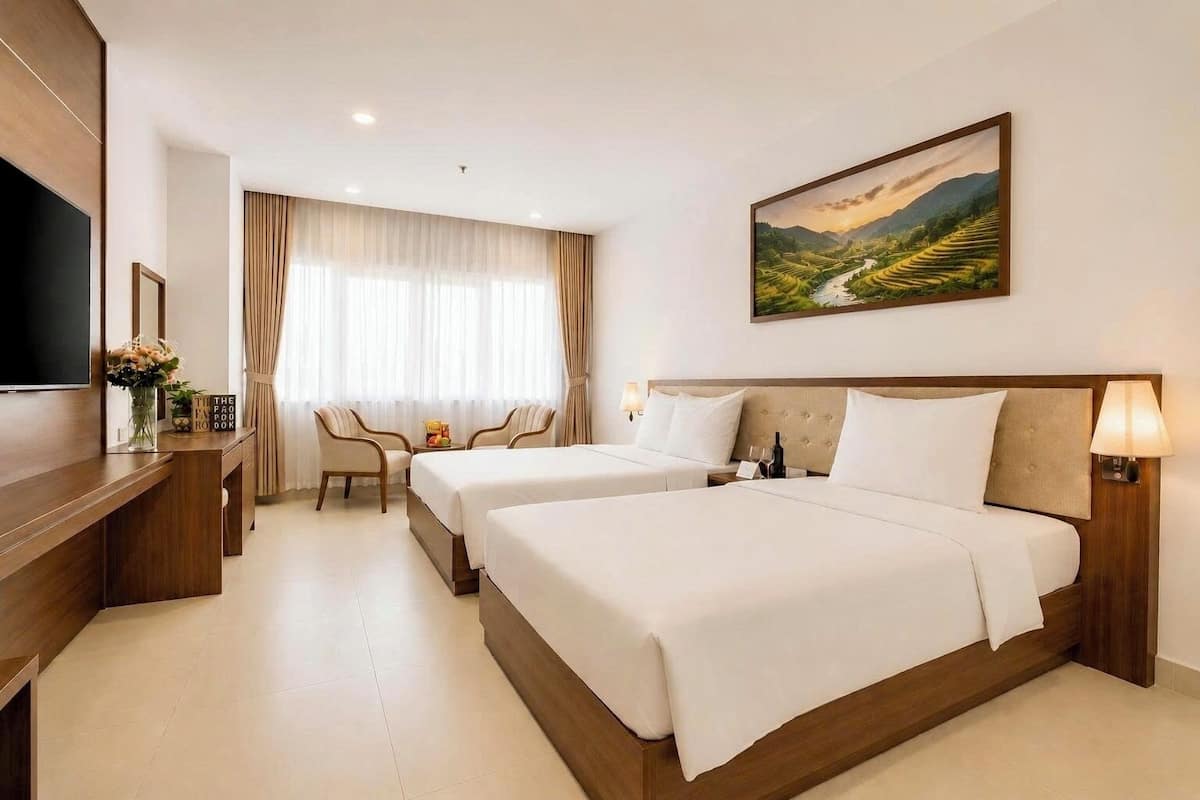 Une chambre d’hôtel avec deux lits, une télévision, un bureau avec un miroir et un tableau au mur.