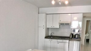 A compact kitchen with white cabinetry, a built-in microwave, and a small sink.