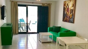 A living room with a green sofa, a white coffee table, and a green cabinet.