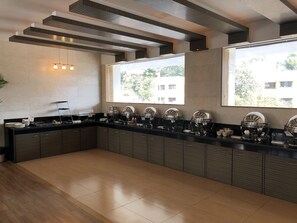 A modern kitchen with a long counter, built-in cabinets, and a window providing a view of the outside. - Resort Silver Hills Lonavala (Mawal)