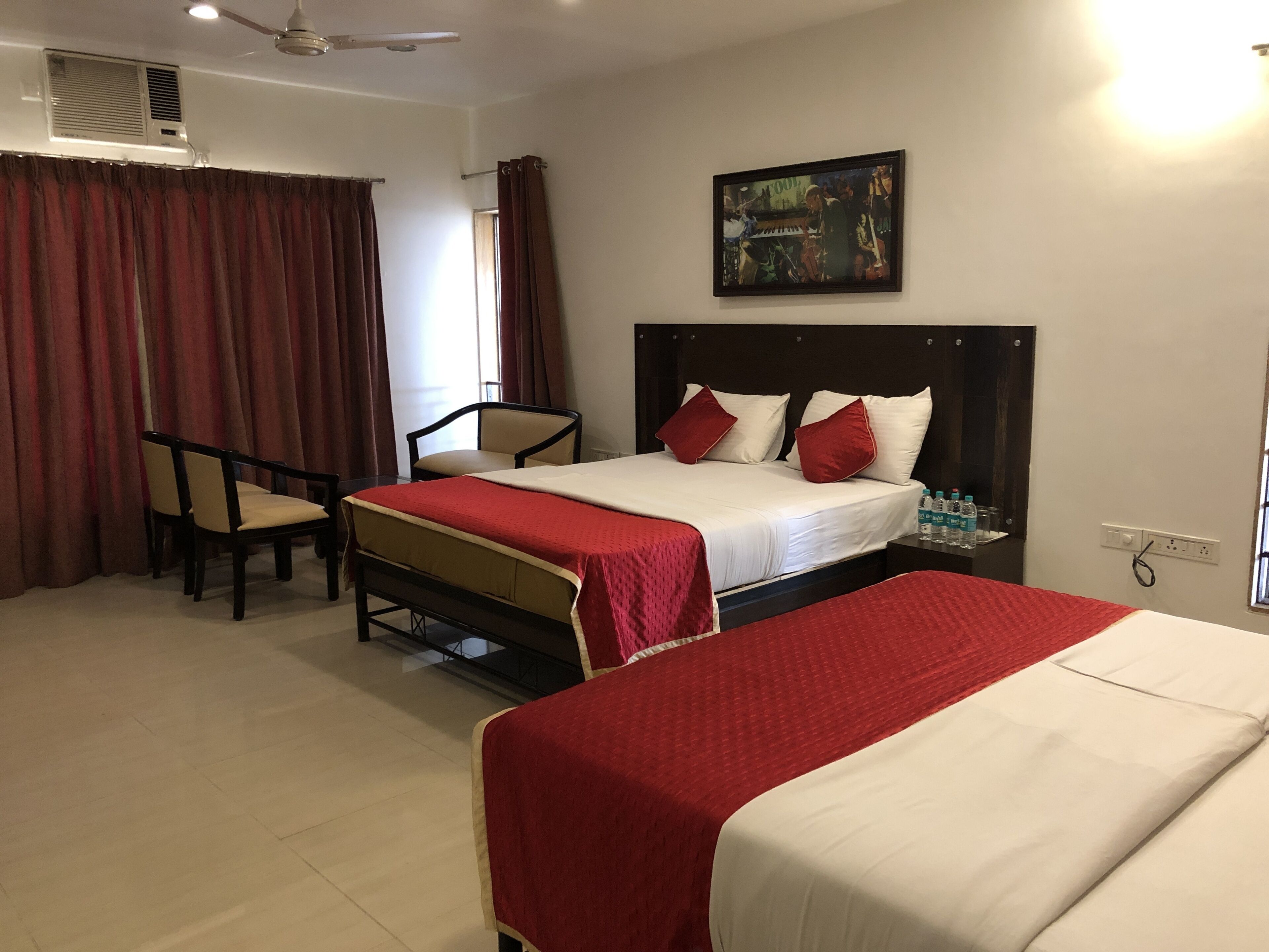 A hotel room with two beds, a desk, and a chair.
