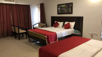 A hotel room with two beds, a desk, and a chair.