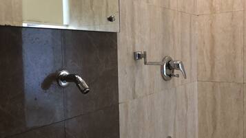 Un baño con lavamanos blanco, espejo y ducha.
