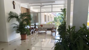 Una habitación amplia y luminosa con un gran ventanal, un ventilador de techo y varias plantas en macetas.