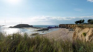 A coastal landscape with a sandy beach, rocky outcrops, and a clear sky. - Résidence Les Iles (Penestin)