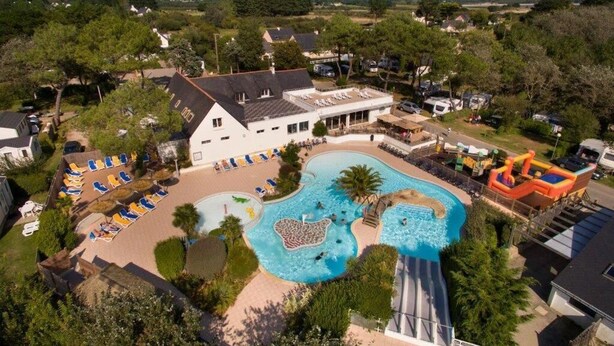 An aerial view of a resort with a large swimming pool, sun loungers, and a slide. - Résidence Les Iles (Penestin)