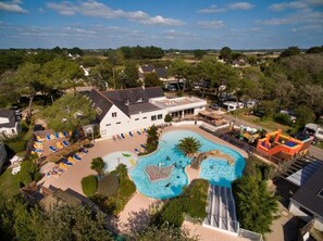 An aerial view of a resort with a large swimming pool, sun loungers, and a slide. - Résidence Les Iles (Penestin)