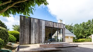 A modern building with a wooden facade, large windows, and a small porch area. - Résidence Les Iles (Penestin)