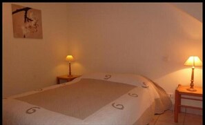 A bedroom with a large bed, two bedside lamps, and a painting on the wall. - Résidence Les Iles (Penestin)