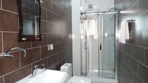 A bathroom with a sink, mirror, toilet, and glass-enclosed shower. - Eliata Hotel & Suites (Lagos)