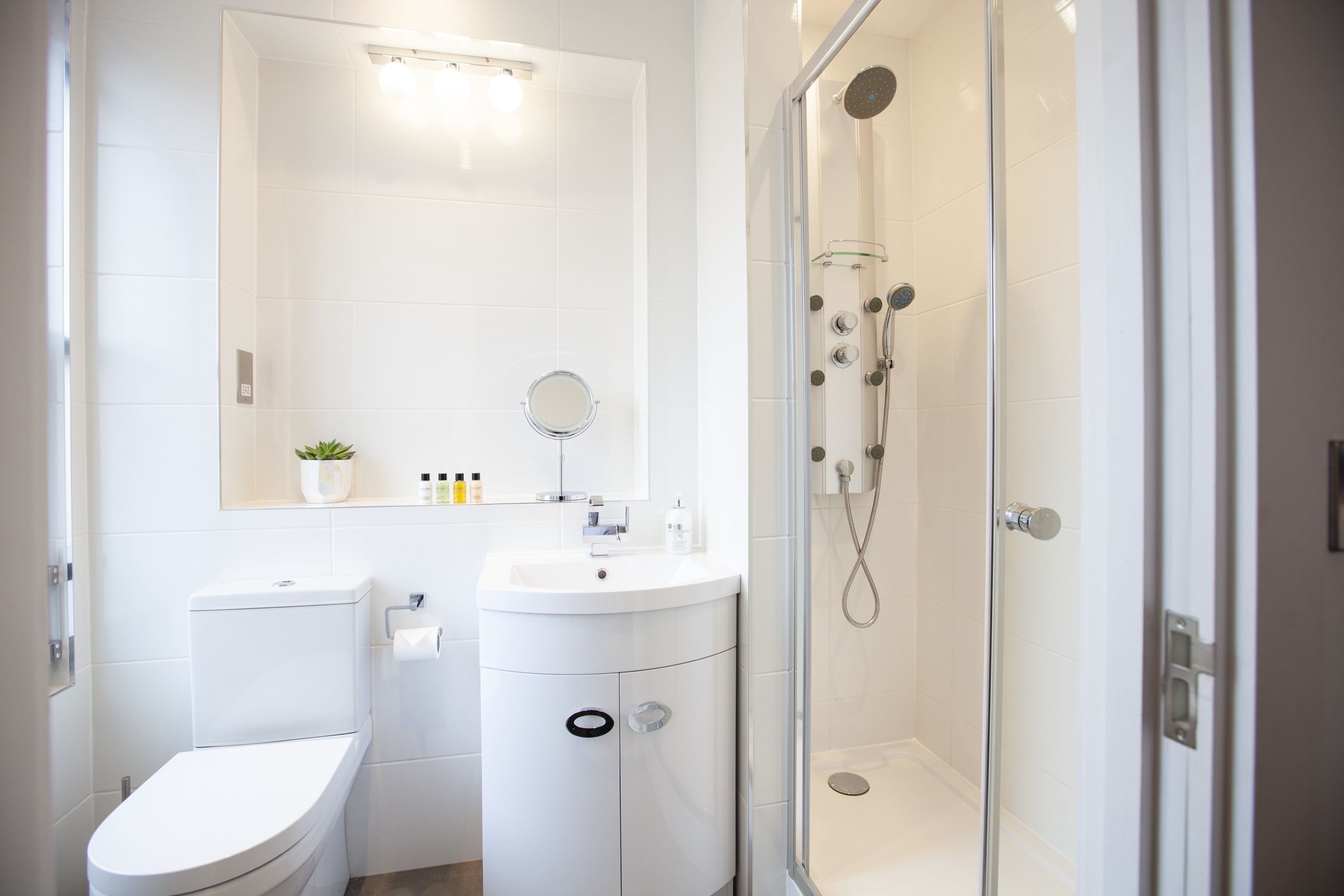 A modern bathroom with a toilet, sink, and glass-enclosed shower.