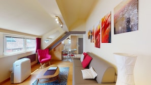 A compact living space with a sofa, a red chair, a table, a radiator, and artwork on the walls. - loft pelletiers city center up to 4 (Strasbourg)