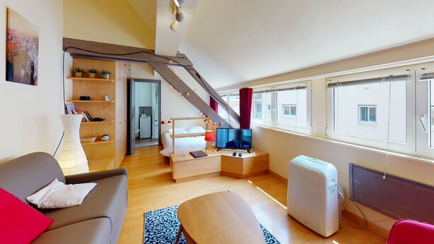 Ein modernes Hotelzimmer mit einer Sitzecke, einem kleinen Tisch, einem Fernseher und einem Heizgerät.