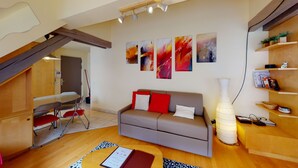 Ein modernes Wohnzimmer mit Sofa, abstrakter Kunst, Essbereich und einer Treppe.