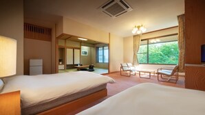 A hotel room with two beds, a desk, chairs, a TV, and a large window with a view of greenery. - Lake View Inawashirosou (Inawashiro)