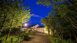 A nighttime view of a building surrounded by trees, with a pathway leading to the entrance. - Lake View Inawashirosou (Inawashiro)