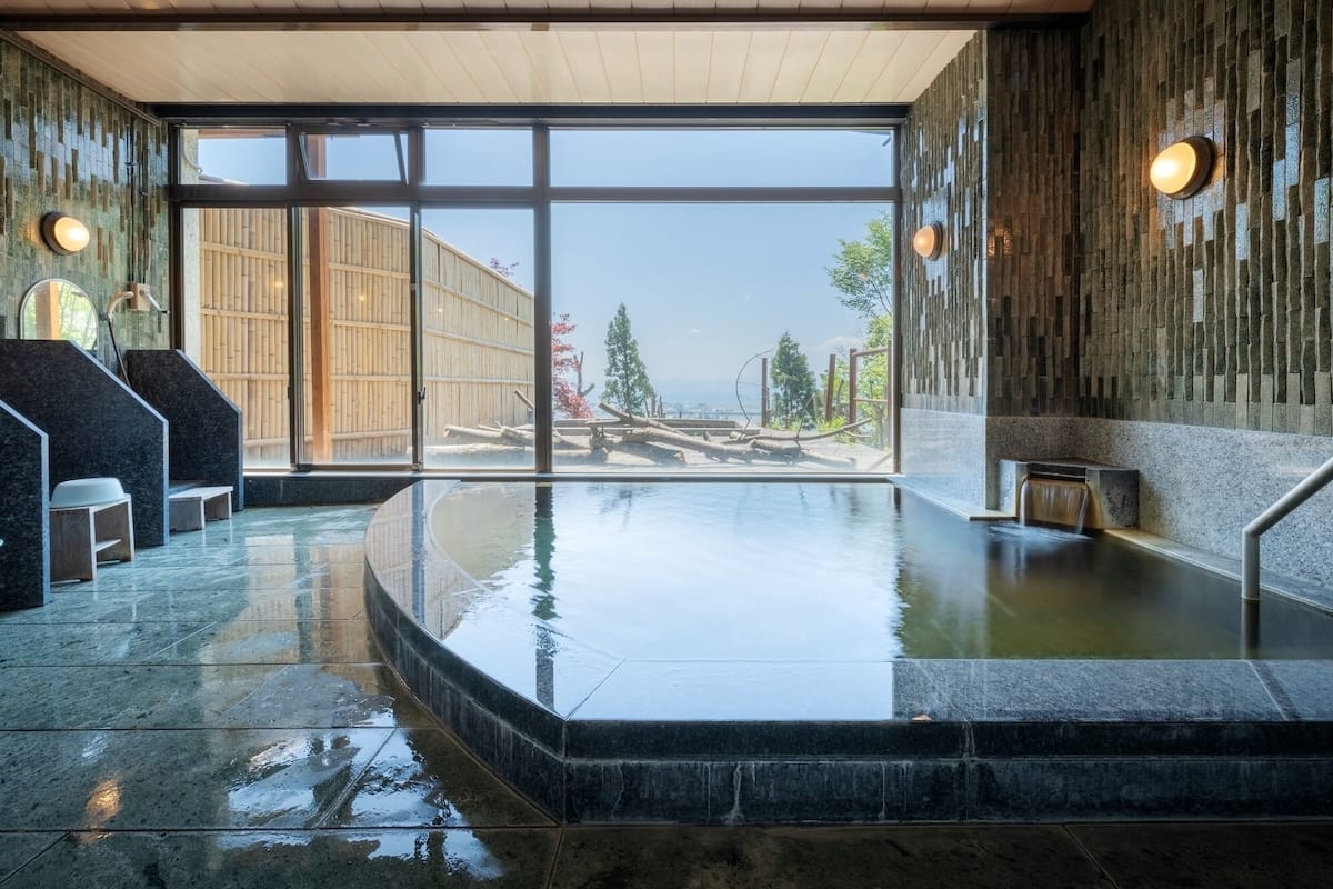 Un espace spa doté d’une grande fenêtre, d’un jacuzzi et d’un mur en bois.