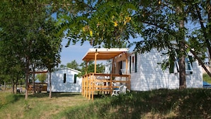 A white wooden house with a porch and a covered seating area. - Ludocamping Mobil-Home (Lussas)