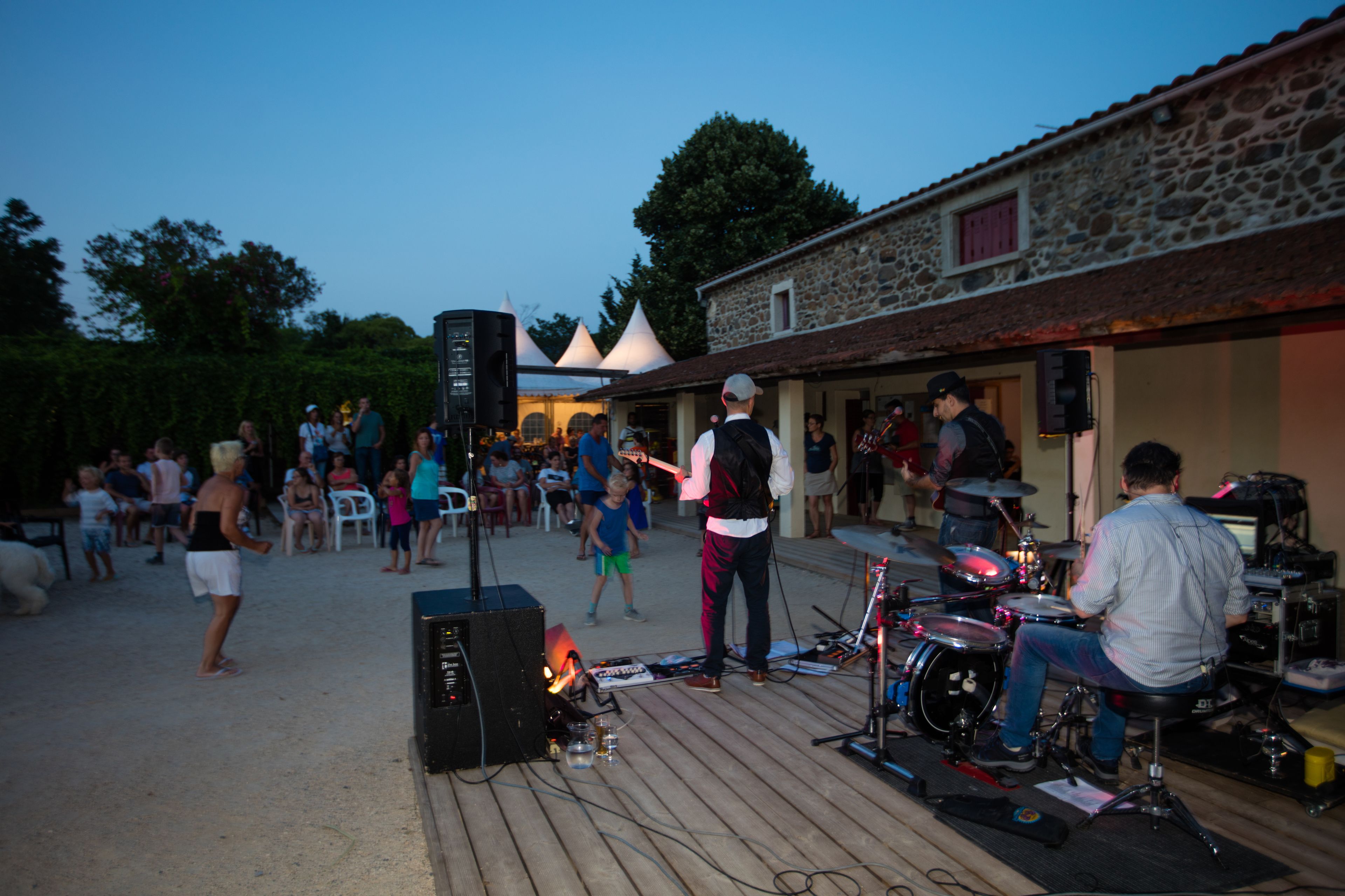An outdoor event with a stage, speakers, and a crowd.