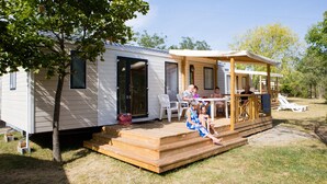 A mobile home with a wooden deck, outdoor seating, and a covered patio area. - Ludocamping Mobil-Home (Lussas)