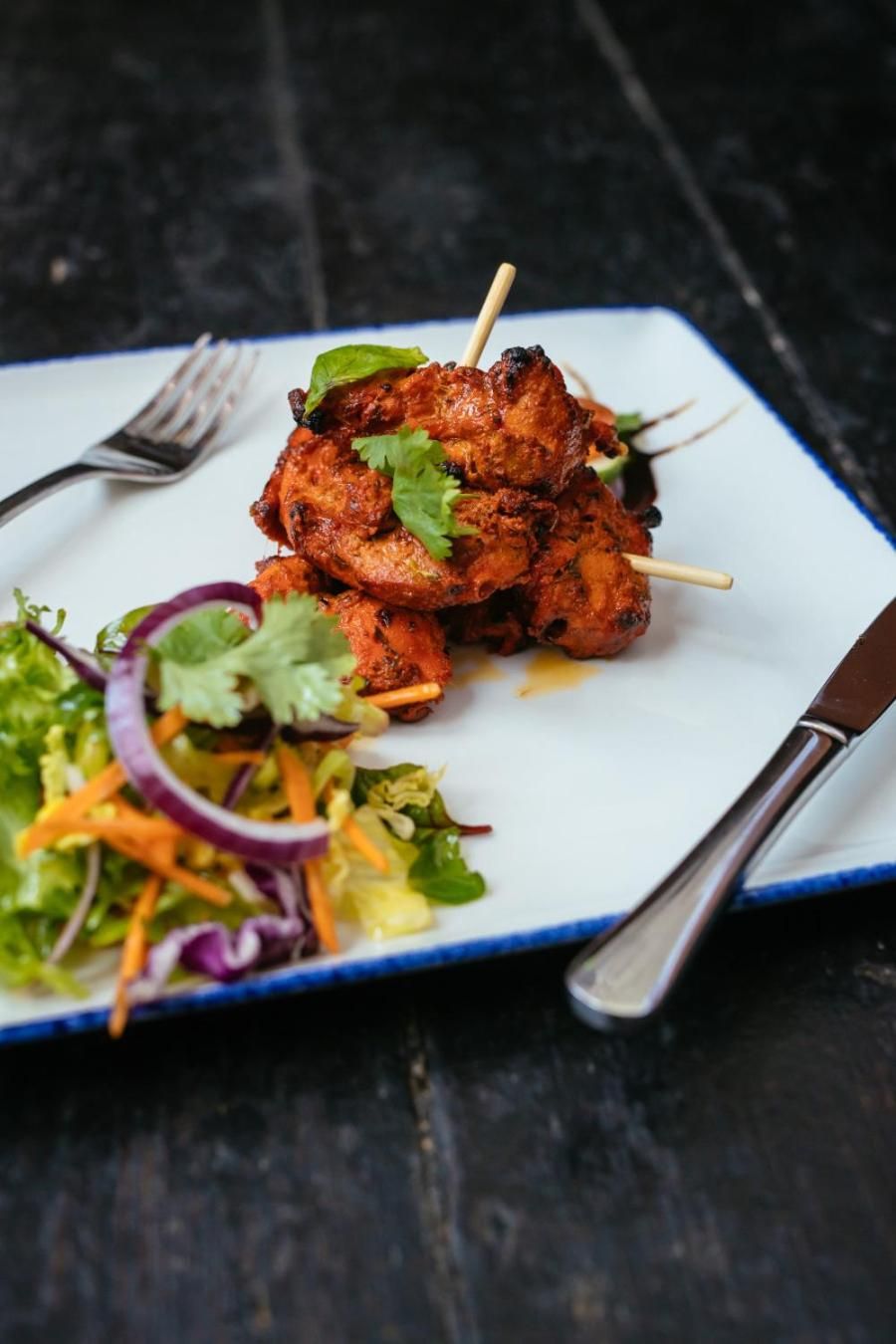 A plate of grilled chicken skewers with a side salad.