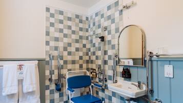 A bathroom with a checkered floor, a wheelchair, a sink, and a toilet.