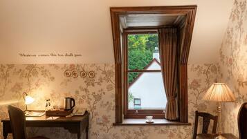 A cozy room with a desk, chair, and a window with curtains.