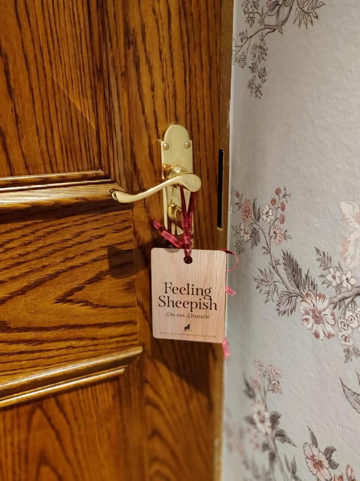 Eine Holztür mit Messingklinke und einem kleinen Holzschild.