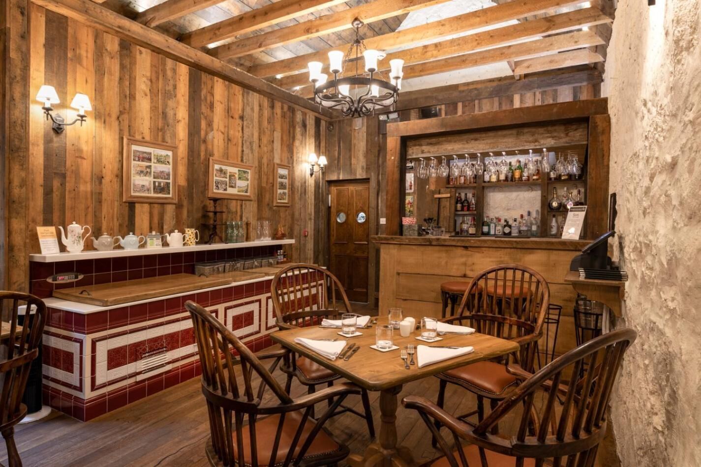 Um interior rústico de madeira com área de bar, cadeiras de madeira e balcão de bar revestido de azulejos.