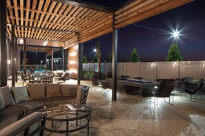 An outdoor patio area with wooden pergola, seating, and a fire feature. - Courtyard by Marriott Lafayette South (Lafayette)