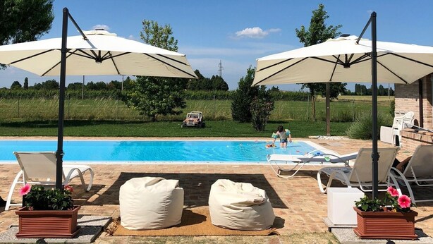 Een zwembadterras met ligbedden, parasols en een zwembad.