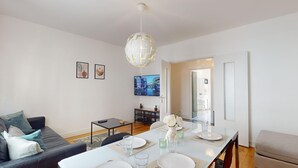 Un soggiorno moderno con divano, tavolo da pranzo e TV a parete.