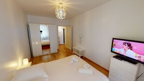 A hotel room with a bed, a television, a desk, and a wardrobe. - aux bons amis parlement orangerie  up to 4 (Strasbourg)