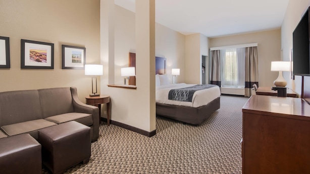 A hotel room with a sofa, a bed, a desk, a TV, and framed pictures on the wall. - Comfort Inn & Suites Rock Hill Northeast (Rock Hill)
