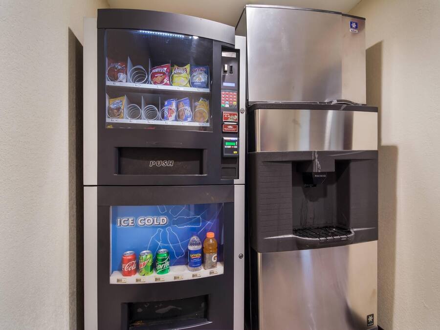 A vending machine with snacks and a water dispenser next to a stainless steel refrigerator.