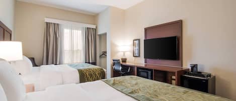 A hotel room with two beds, a desk with a chair, a television, a coffee maker, and a window with curtains.