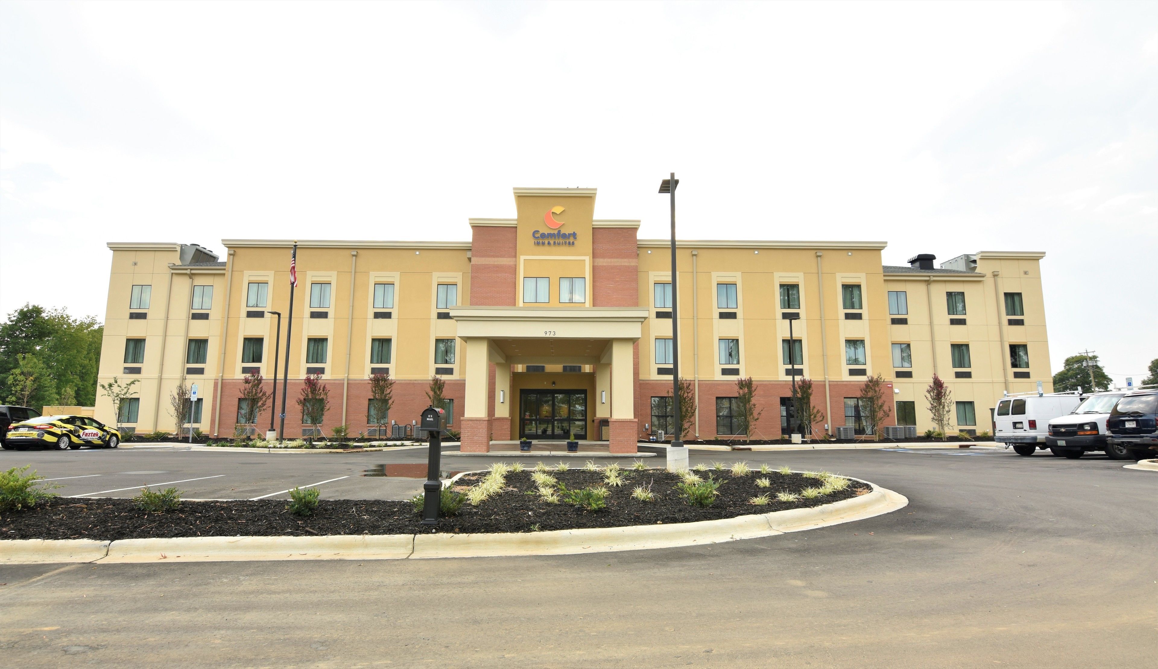 Un hotel Comfort Inn & Suites con fachada de ladrillo, múltiples ventanas y un estacionamiento.