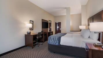 A hotel room with a bed, desk, chair, and two lamps.