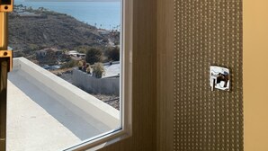 Una habitación con un ventanal grande que ofrece vistas a un paisaje costero, una pared con diseño y una rejilla en el techo.