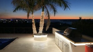 Un patio exterior con piscina, una parrilla y un área de estar con pileta y muebles empotrados.