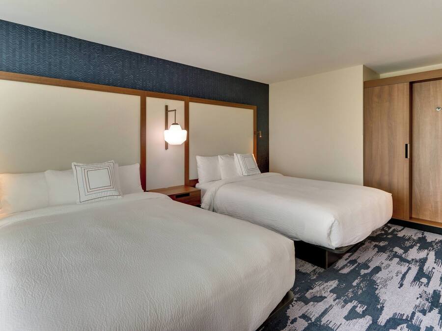 Ein Hotelzimmer mit zwei Betten, einem Nachttisch, einem Holzschrank und einem gemusterten Teppich.