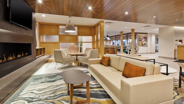 Un hall d’hôtel moderne doté d’une cheminée, d’un espace salon et d’un coin repas.
