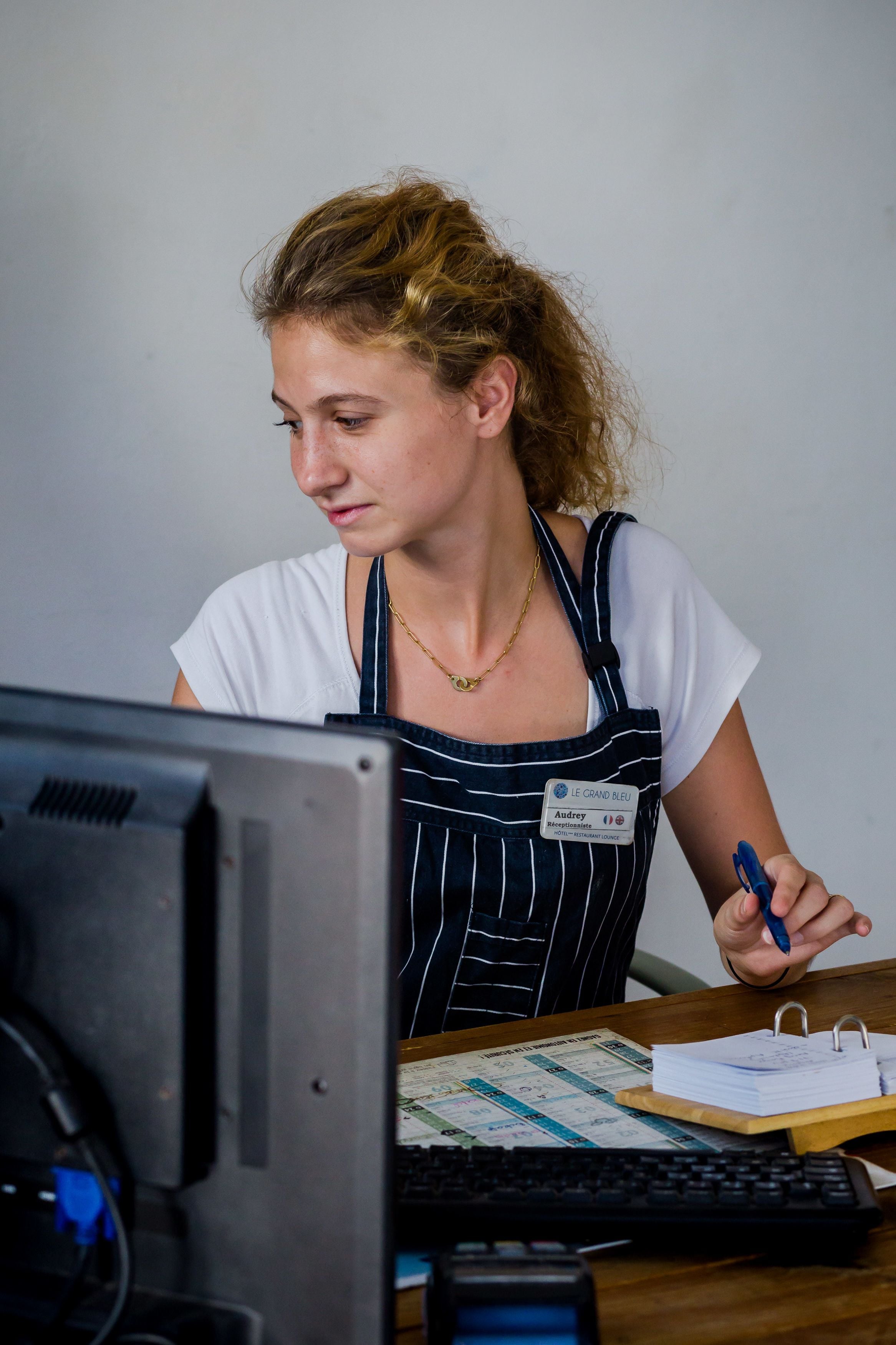 A person sitting at a desk with a computer, a keyboard, and some papers.