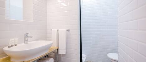 A modern bathroom with a white sink, mirror, and toilet.